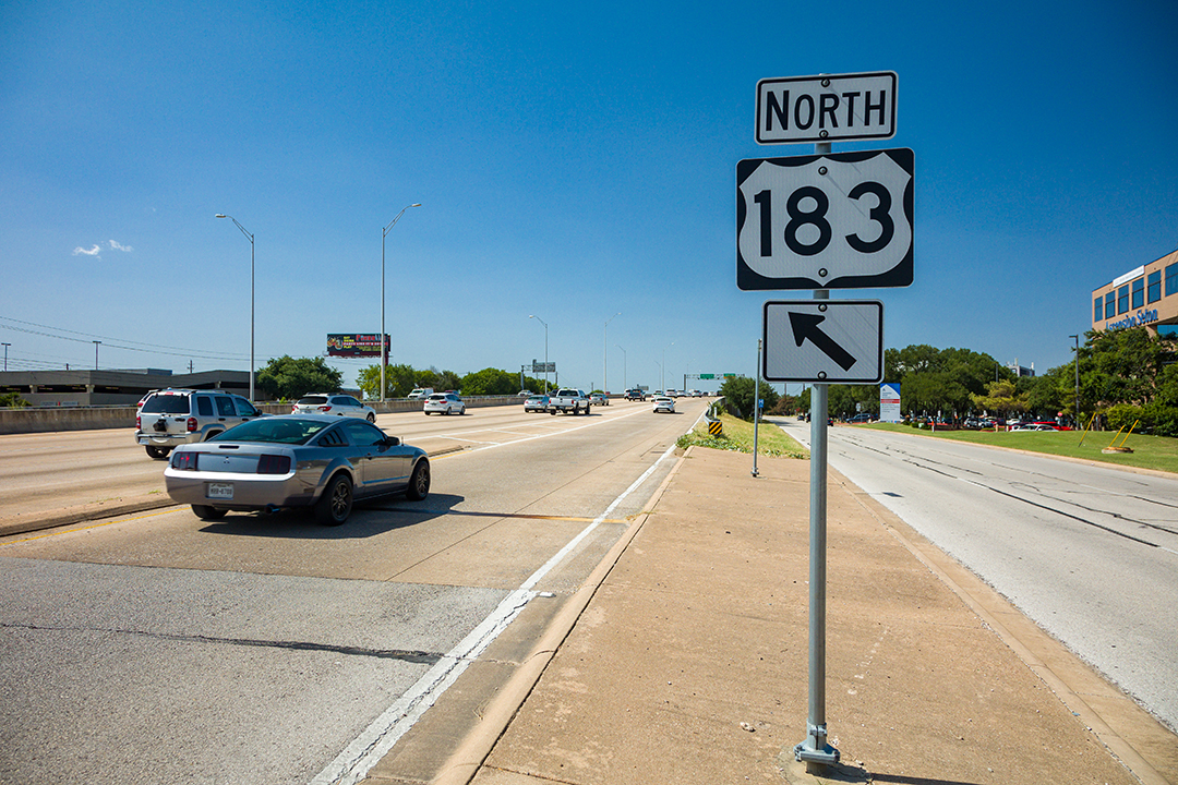 A roadway sign between general purpose lanes and the frontage road labeled 