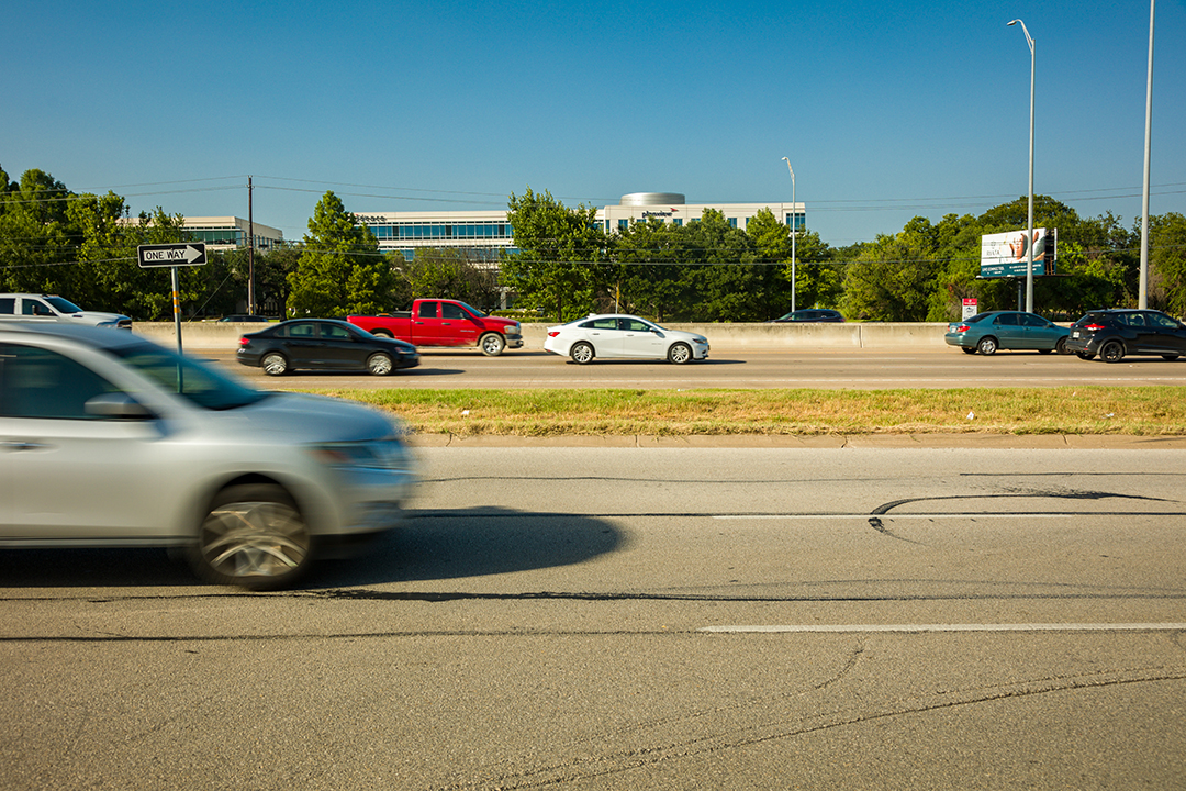 Vehicles in motion driving along the US 183 general purpose lanes and frontage road.
