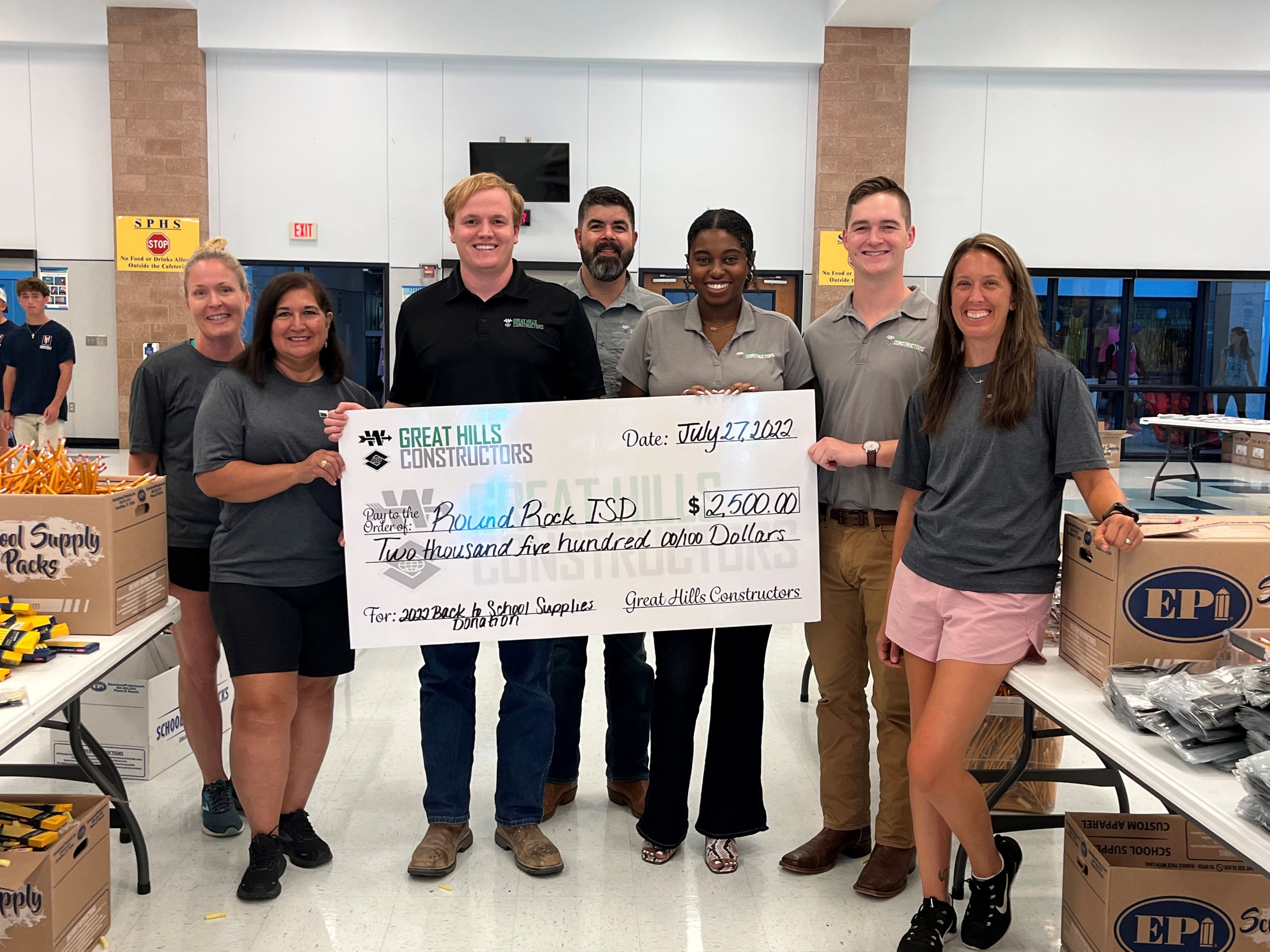 The Great Hills Constructors team stands with a large novelty check for $2,500 made out to Round Rock ISD for Back to School Supplies.