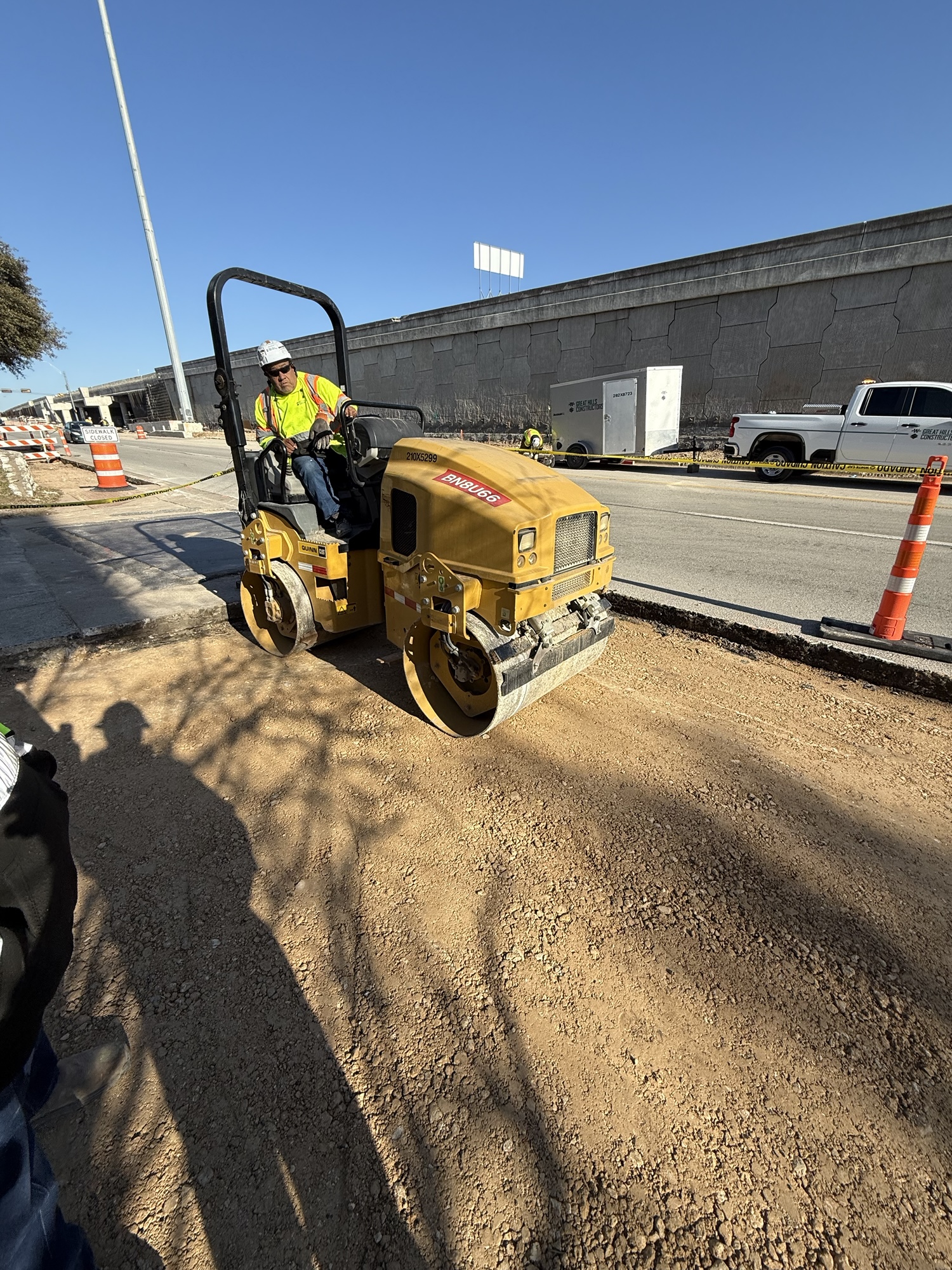 Crews compact subgrade for driveway construction.