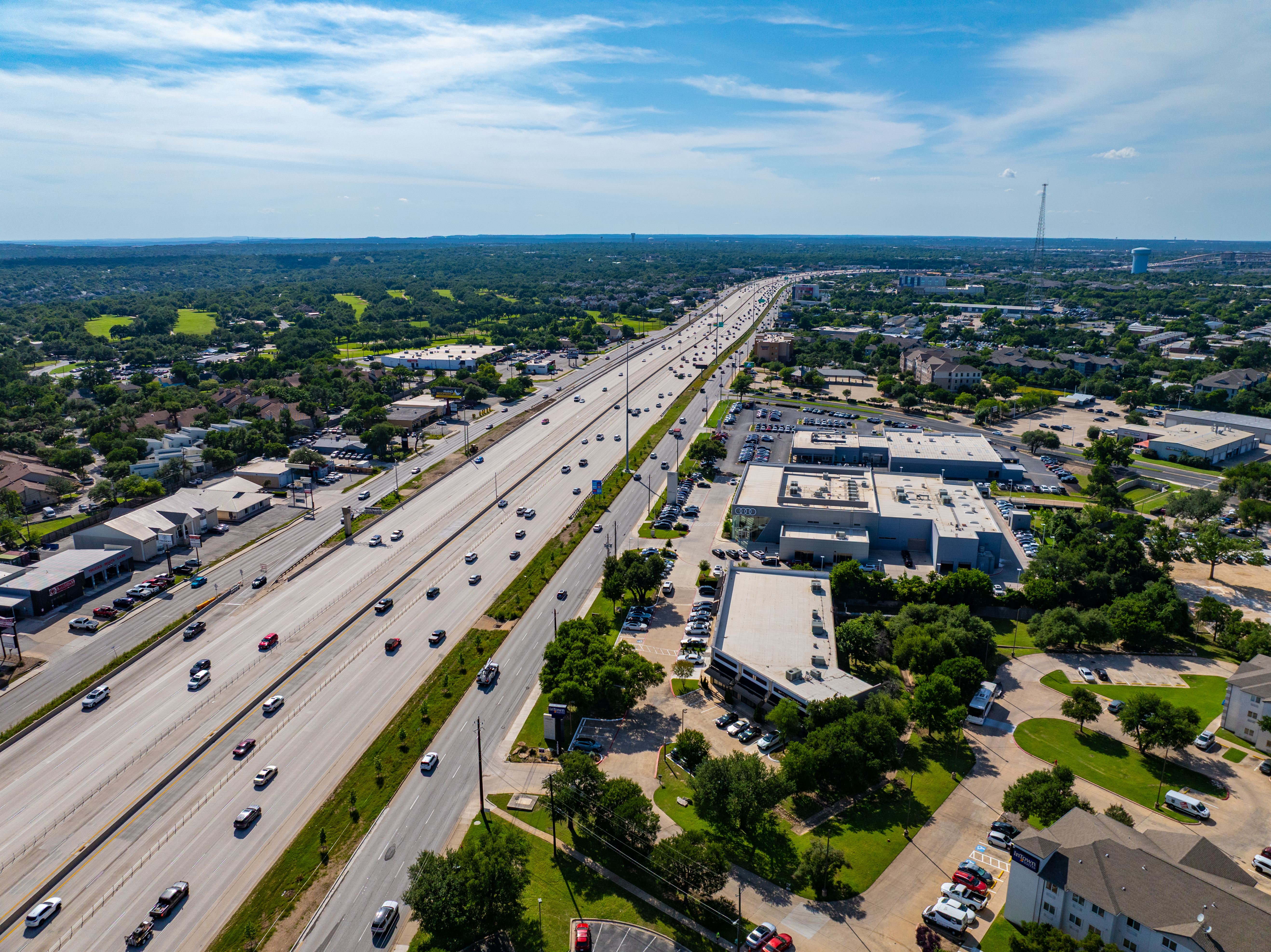 Right-angled aerial view of the 183 North Mobility Project at Anderson Mill Road, highlighting the northbound and southbound express lanes, mainlanes, and frontage roads adjacent to commercial developments and car dealership.