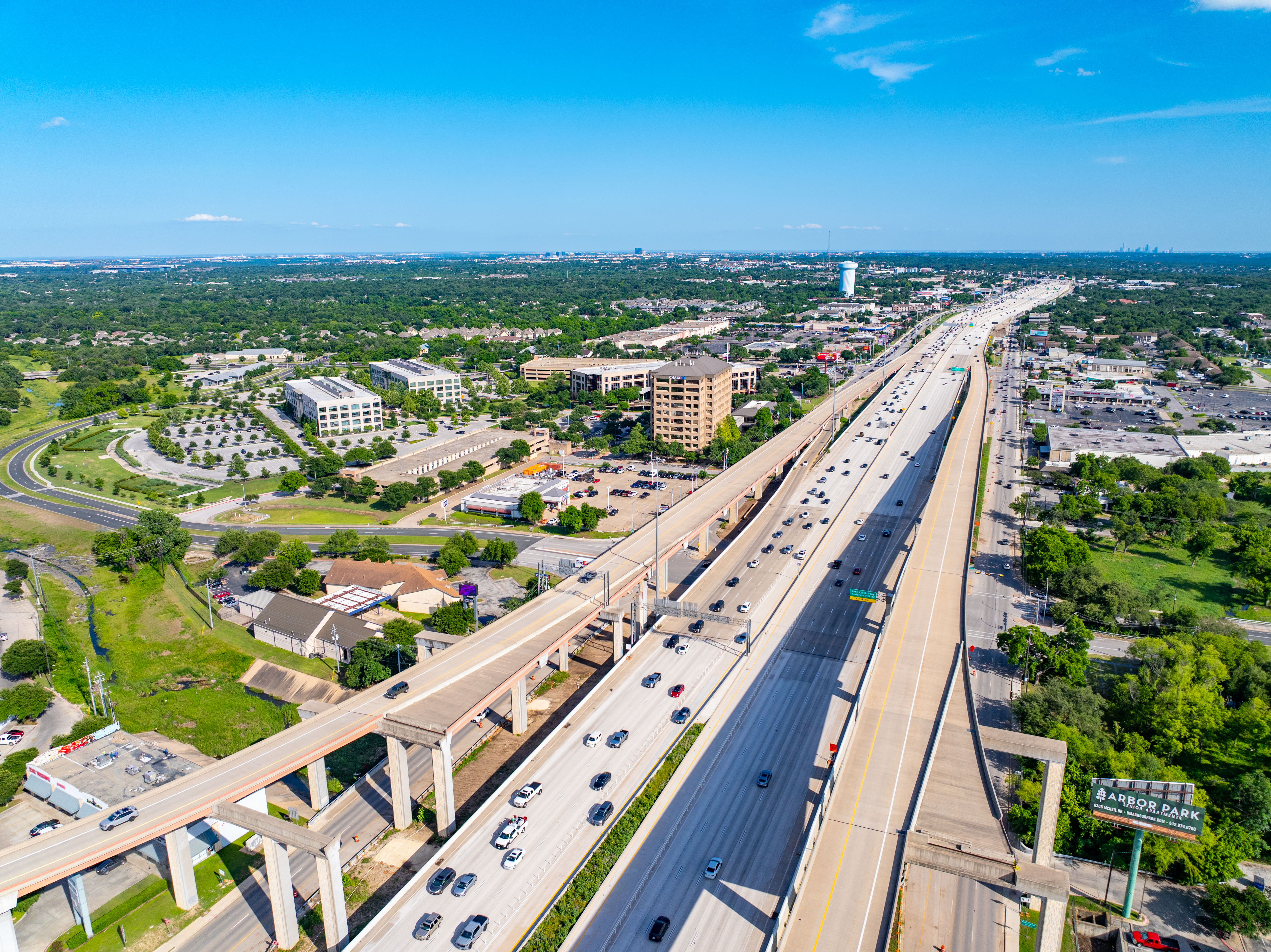 •	Right-angled aerial view of the 183 North Mobility Project near Texas Children's Hospital, showing the northbound and southbound direct connector entrances. Express lanes, mainlanes, and frontage roads are visible in both directions.