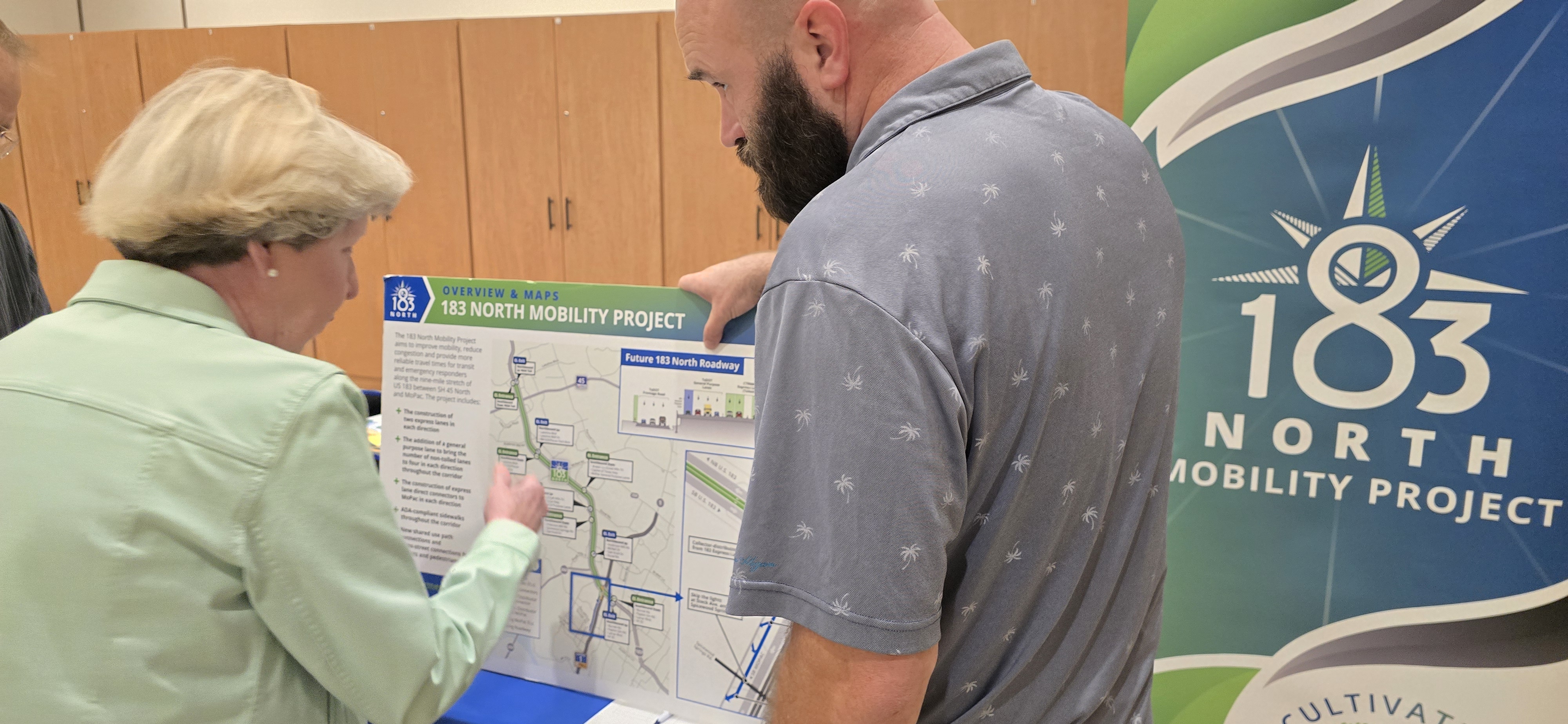 Man holds map illustration poster while woman studies the information